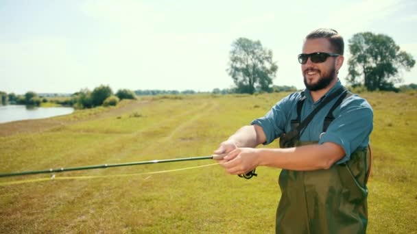 Člověk rybář, rybaření, držení rybářské tyčinky, předhazovávání návnady, otáčející se cívka — Stock video