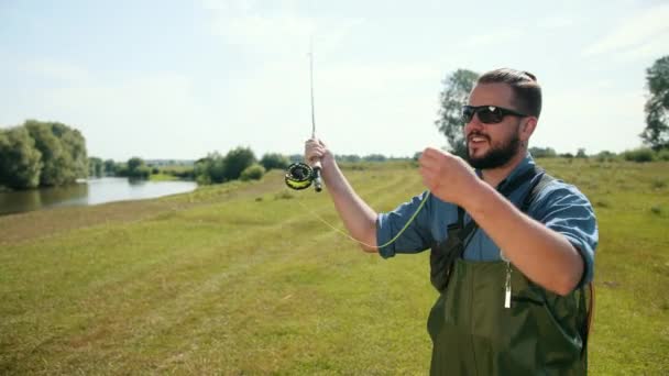 Mann fischt, angeln, Angelrute in der Hand, Köder spannen, Spinnrolle — Stockvideo