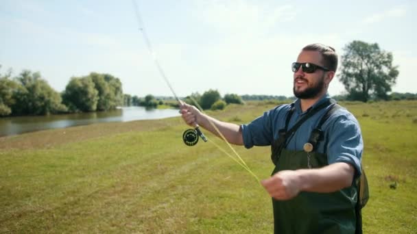 Homme pêcheur, pêche, tenir une canne à pêche, appât à cordes, bobine filante — Video