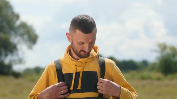 Ung man med kort hår och skägg, poserar och ler framför kameran — Stockvideo