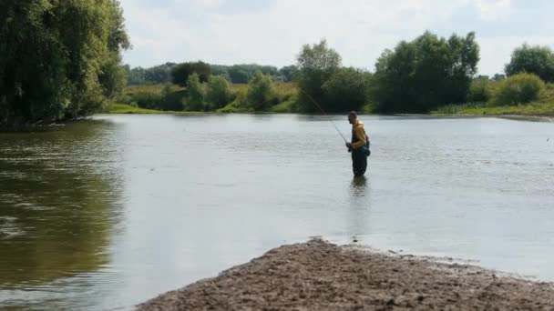 Mannelijke visser gooit een vlotter, vissen op de rivier, staande in het water — Stockvideo