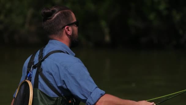 Fischer wirft einen Schwimmer, ein Mann fischt auf dem Fluss, im Wasser stehend — Stockvideo