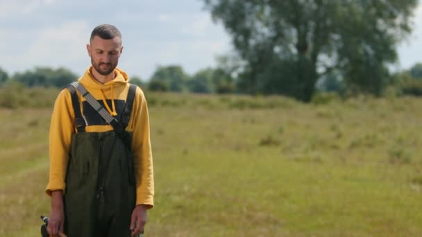 Man med kort hår och skägg, med fiskespö i händerna, en fiskare som poserar — Stockvideo