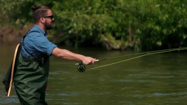 Рибалка кидає поплавок, чоловік рибалить на річці, стоїть у воді — стокове відео