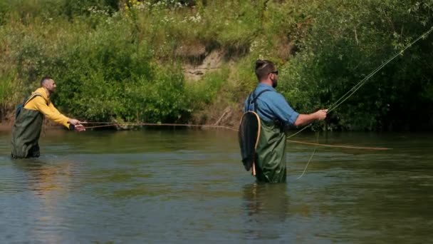 Pesca, dos hombres pescando en el río, de pie en el agua, una pequeña corriente — Vídeo de stock