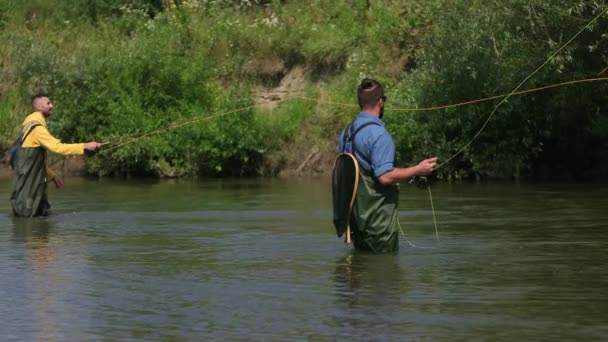 Pesca, dos hombres pescando en el río, de pie en el agua, una pequeña corriente — Vídeo de stock