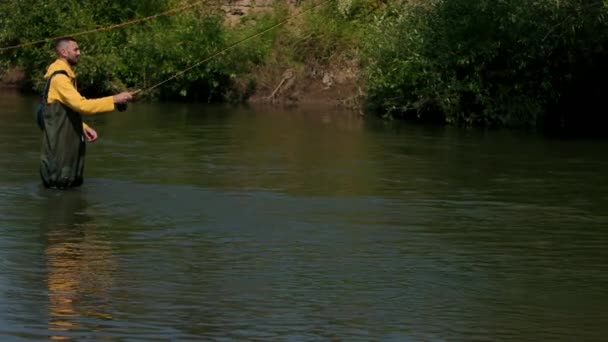 Mannelijke visser gooit een vlotter, vissen op de rivier, staande in het water — Stockvideo