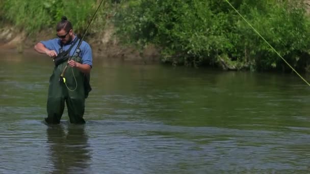 Homme pêcheur, tenant une canne à pêche, à la recherche d'appâts dans un petit sac — Video