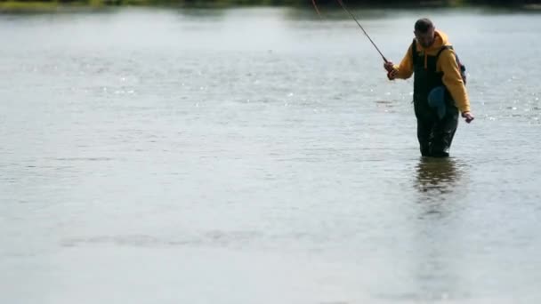 Pescador lanza una carroza, coge un pez a mano en el río, de pie en el agua — Vídeo de stock