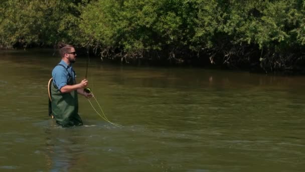 Рибалка кидає поплавок, чоловік рибалить на річці, стоїть у воді — стокове відео