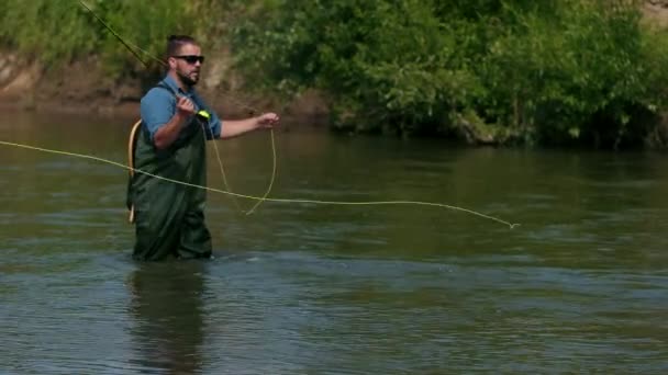 Balıkçı bir şamandıra atar, nehirde balık tutmak, suda duran bir adam — Stok video