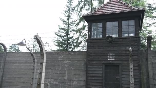 Sicherheitsturm aus dunklem Holz und alten Ziegeln, der hinter einem Zaun aus Stacheldraht steht — Stockvideo