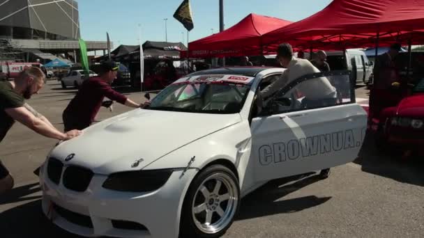 Quatro homens jovens empurrando sob o dossel, esportes brancos deriva carro de corrida — Vídeo de Stock