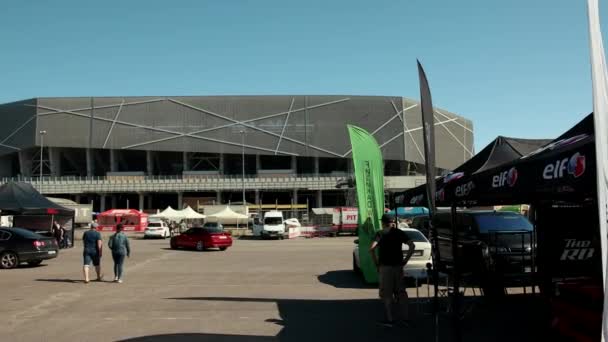 Красный спортивный автомобиль для дрифт-рейсинга, проходящий на территории рядом с большим зданием стадиона — стоковое видео