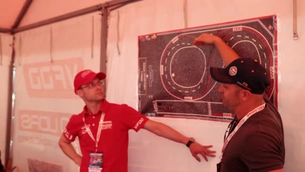 Due uomini mostrano sulla mappa dove è disegnata la pista di gara, un piano d'azione per le auto da corsa — Video Stock