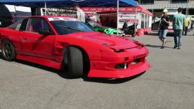 Sokak yarışları için parlak kırmızı bir araba. Ön camında bir çıkartma var.