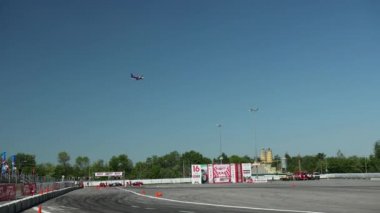 high in sky above the stadium, where race on passenger sports cars, flying plane
