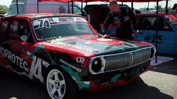 Homem piloto, esfrega carro esporte vermelho coberto com adesivos para corridas de drift de rua — Vídeo de Stock