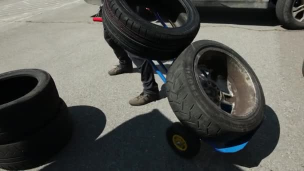 Людина в чорному одязі несе синій візок, два колеса з приводами — стокове відео