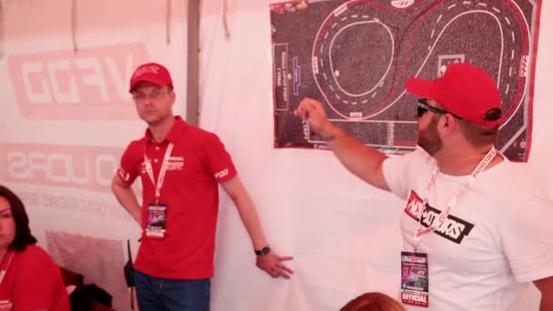 Dois homens mostram no mapa onde a pista de corrida é desenhada, um plano de ação para carros de corrida — Vídeo de Stock