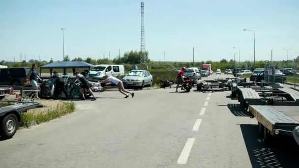 Jóvenes empujando un coche de carreras de deriva deportes negro, pegatinas pegadas — Vídeo de stock