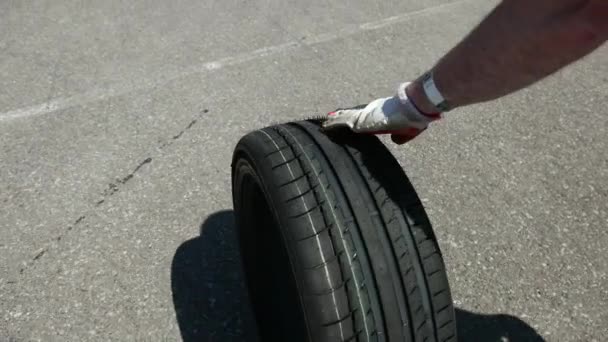 Homme porte un pneu, dans la zone où il ya beaucoup de voitures de course de sport — Video