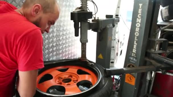 Человек на специальной машине для шин, заменяющей резину на диске — стоковое видео
