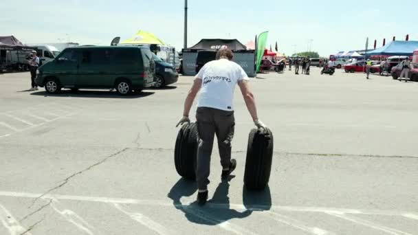 Homem rola duas rodas com discos brancos, onde há muitos carros — Vídeo de Stock