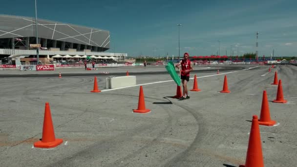 Mladý muž mávající vlajku, zelené auto pro pouliční závodění, jde na trať — Stock video