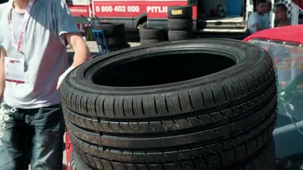 Hombre toma un neumático y lleva, de un coche de carreras de deportes para las carreras — Vídeos de Stock