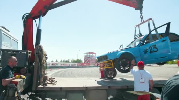 Эвакуатор забирает синий разбившийся спортивный автомобиль, сошедший с трассы — стоковое видео