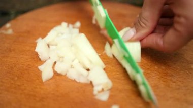 kadın ahşap bir tahta, yeşil bıçak, soğan küçük parçalar üzerinde keser