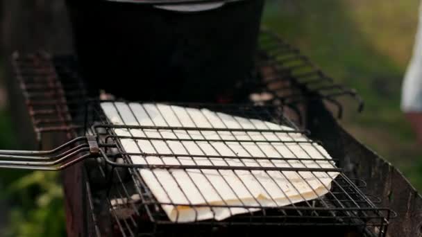 Man op de grill, het roosteren van grote Pita broodjes, in het vuur, in de namiddag op straat — Stockvideo