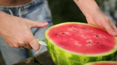 genç adam dilimler halinde bıçak keser, büyük olgun kırmızı karpuz, sokakta, Güneşli gün
