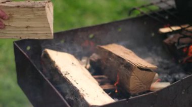 adam ızgara birkaç odun atar, sokakta öğleden sonra, küçük ateş yaktı