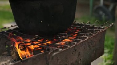 ızgara üzerinde yangın yanıklar ve çanak büyük dökme demir kazanda pişirilir
