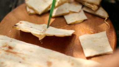 adam doğada bir piknikte yeşil bir bıçak ile küçük parçalar halinde pide ekmek keser