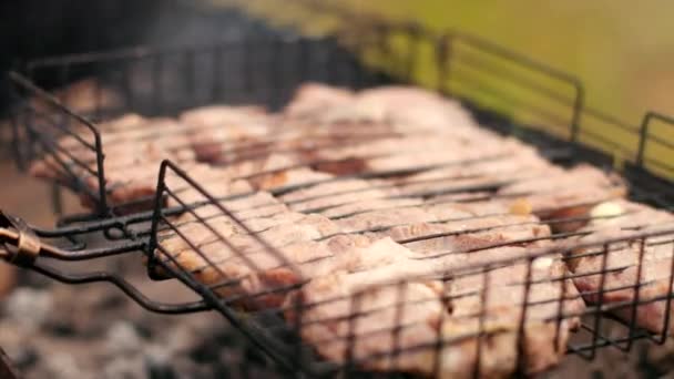 Mann bereitet große Fleischstücke auf dem Grill zu, dreht sich zum Braten — Stockvideo