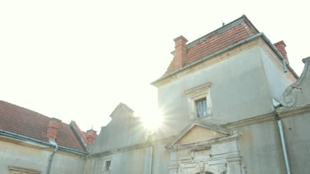Starý hrad s otlučenou zdí a červenou střechou, starými velkými branami a okny — Stock video