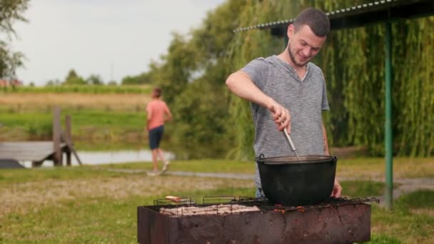 Люди готують їжу на грилі на пікніку, красиву природу — стокове відео