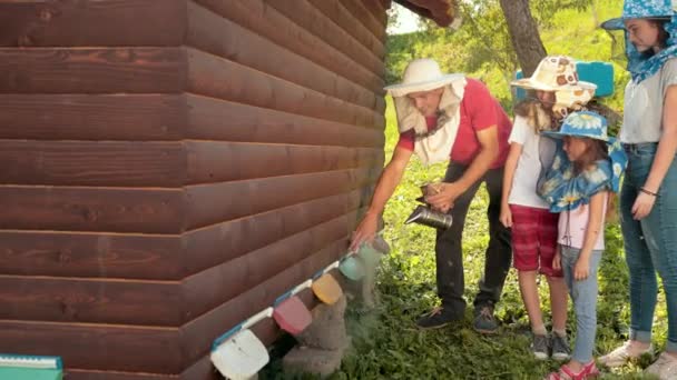 Пчеловод в специальной одежде для пчеловодства, держит курильщика, чтобы успокоить пчел — стоковое видео