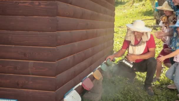 Beekeeper in special clothes for beekeeping, holding a smoker to calm the bees — Stock Video