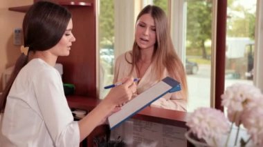 tıbbi cüppe hemşire resepsiyonda kadın müşteriye tavsiye sağlar