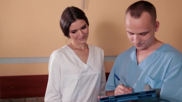 Enfermeira e médico de vestido médico azul, stand na recepção e consultar — Vídeo de Stock