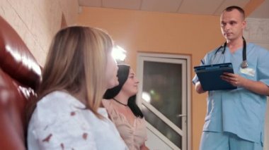 lobide kanepede oturan üç kız, adam doktor danışır