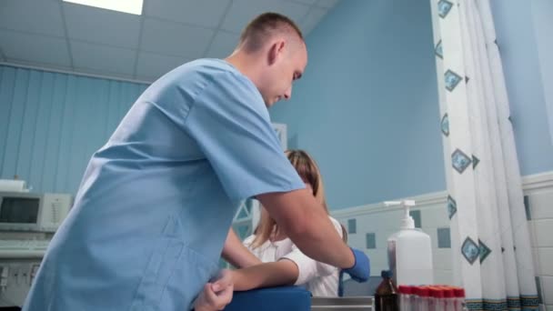 Arzt bindet Tourniquet mit der Hand zusammen, der Patient sitzt und wartet auf Tests — Stockvideo