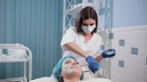 Infirmière médecin fait femme massage facial, provoque masque blanc avec brosse — Video