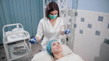 mavi eldiven hemşire doktor, ışık hareketleri ile bir kadın yüz masajı yapar