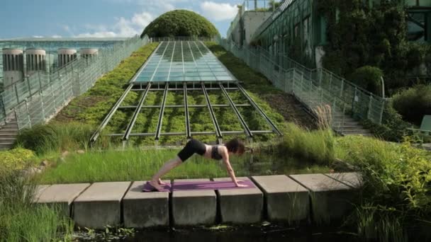 Chica joven en ropa deportiva negro haciendo yoga al aire libre, realiza varios ejercicios — Vídeo de stock