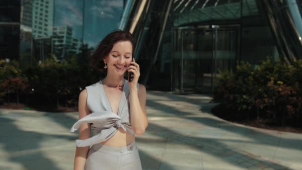 Negocios, mujer joven, morena, sosteniendo un teléfono inteligente hablando, decisión positiva — Vídeos de Stock